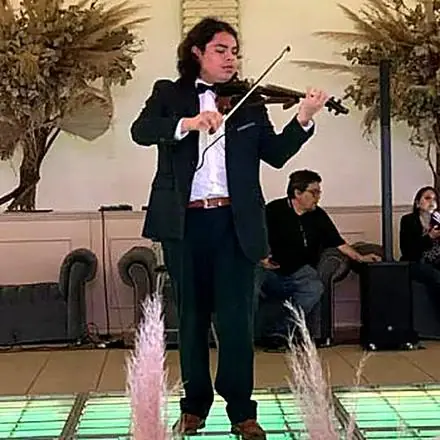 Daniel Hiram tocando el violín en smoking en un evento